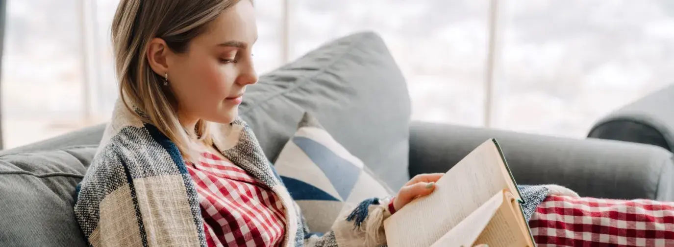 woman reading in red checkered pajamas